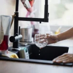 A glass being filled with tap water at a kitchen sink - Habit, Taste and Trust: The Real Reasons Bottled Water Endures