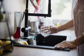A glass being filled with tap water at a kitchen sink - Habit, Taste and Trust: The Real Reasons Bottled Water Endures