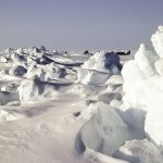 broken arctic sea ice floating on dark ocean water