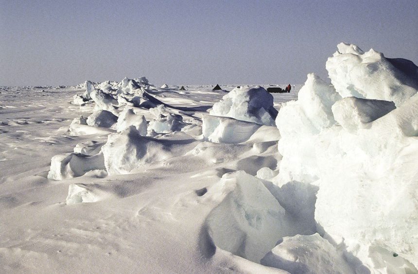 broken arctic sea ice floating on dark ocean water